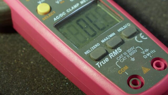 Closeup finger presses buttons on electronics clamp multimeter tool