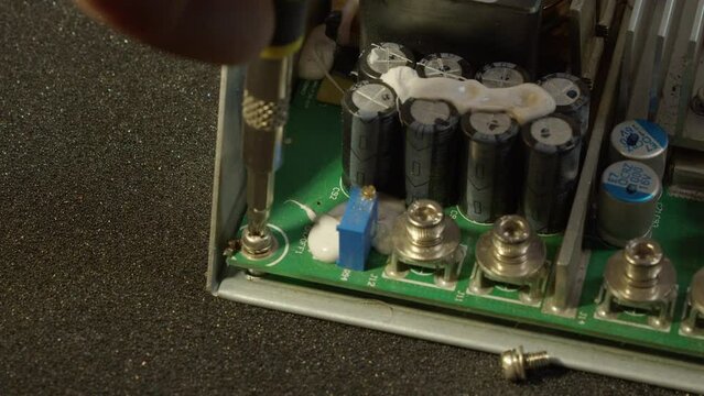 Close-up: Screwdriver removes circuit board from electronics chassis