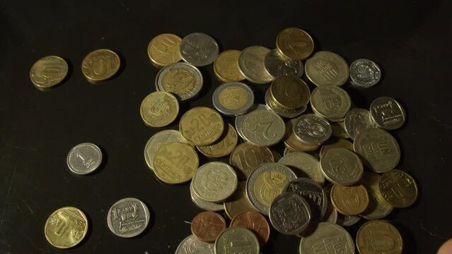 Close up on dark background, various nation coins are flung onto table
