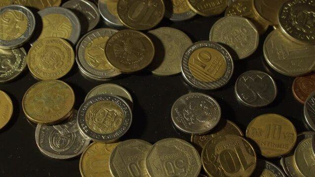 Money: Rand, Ruble, Sol coins tossed onto dark table, close up view