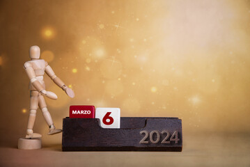 March's lively presentation: Wooden figure directs to the sixth day on a bright calendar with warm-toned hues. - obrazy, fototapety, plakaty