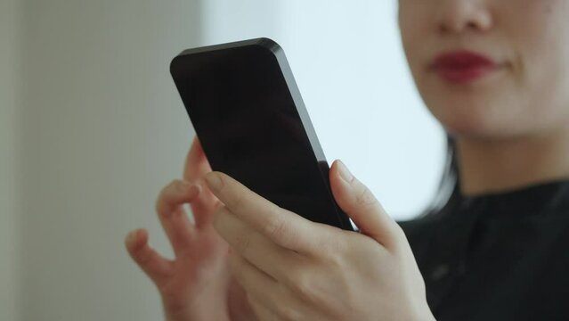 スマートフォンの画面を見る女性の手元