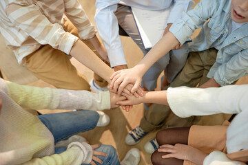 Top view closeup of children stacking hands and huddling celebrating success and teamwork in schoolwith copy space - obrazy, fototapety, plakaty