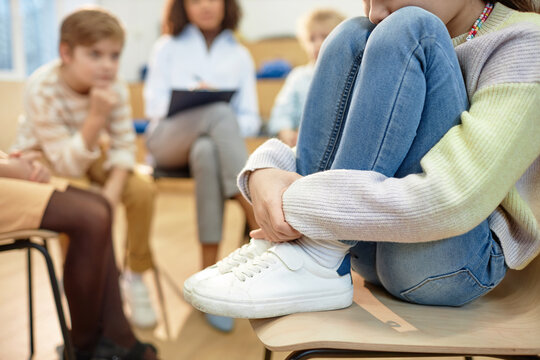 Close up of depressed young girl hugging knees and sharing mental health problem during support group for childrenwith copy space