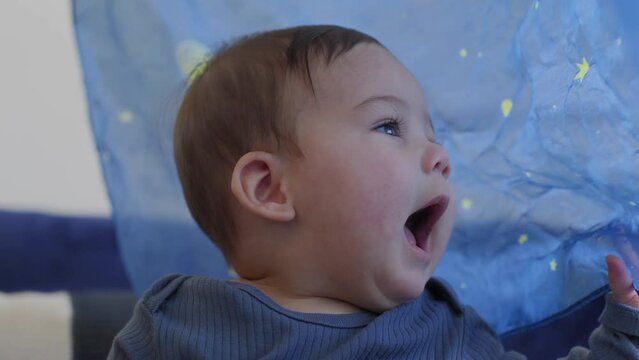 Baby smiling and laughing playing with a blue silk with yellow stars in slow motion