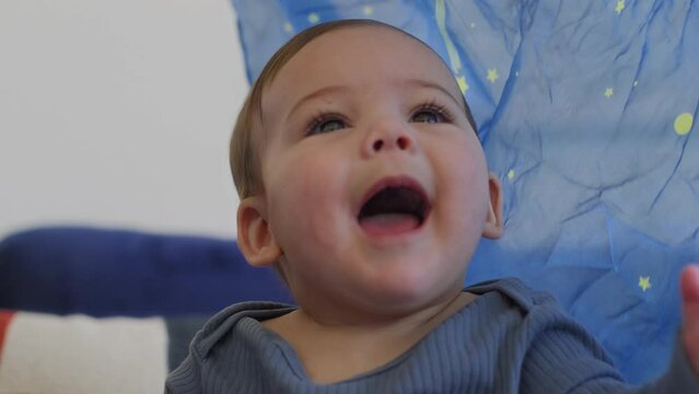 Baby smiling and laughing playing with a blue silk with yellow stars in slow motion