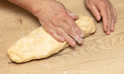 A woman kneads dough with her hands