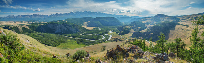 Above a picturesque mountain valley with a river, evening light, panoramic view