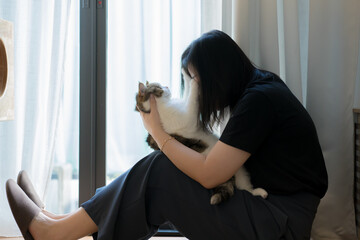 wellness and wellbeing concept with asian woman sit and play with her cat in livingroom