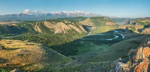 Above a picturesque mountain valley with a river, evening light, panoramic view © Valerii