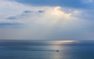 Sunlight pouring through the clouds reflects on the surface of the sea. Morning sunrise scenery on the sea