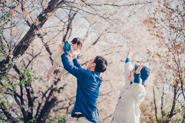 桜と高い高いされる赤ちゃんと家族