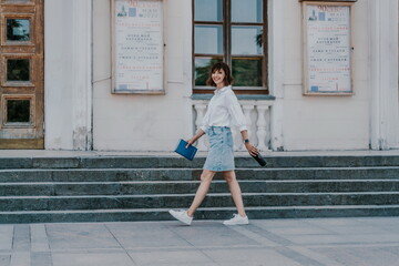 Woman staircase city. A business woman in a white shirt and denim skirt walks down the steps of an ancient building in the city