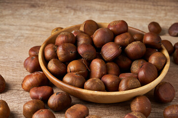 pile of chestnut in wood bowl on wooden table background. chestnut in wood food rustic background