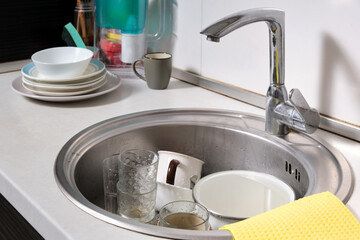 Close-up of a large metal sink in the kitchen at home with dirty dishes.