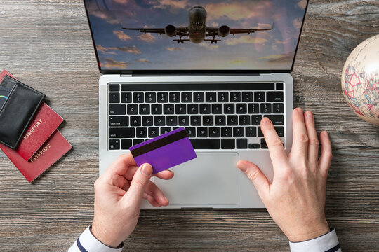 A man is booking air tickets for a trip and traveling on a laptop. Online payment by bank or credit card. Conceptual image.