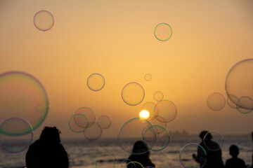 Lots of soap bubbles in the sky at sunset with people