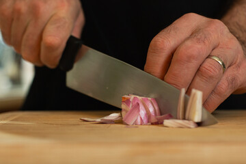 Married man slicing shallots on wooden cutting board