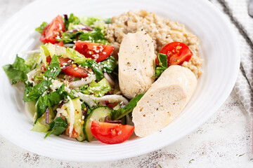 Breakfast oatmeal porridge with boiled homemade chicken sausage and fresh salad. Healthy balanced food. Trendy food.