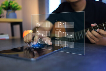 Man learning acoustic guitar chords chart on tablet is music self learning on internet
