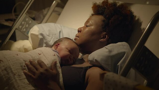 Black Woman with Curly Hair Resting in Delivery Room With Infant Child