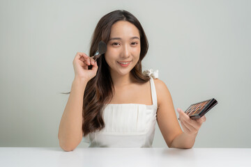Portrait of a beautiful young Asian girl applying dry powder Makeup with cosmetic cushion on her...