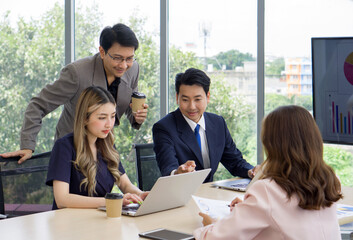 Business professional collaborating with enthusiasm while examining data on a laptop in a contemporary office setting.