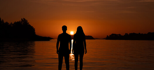 sylwetka mężczyzny i kobiety na plaży przy zachodzie słońca	 - obrazy, fototapety, plakaty