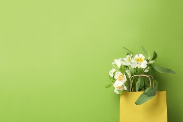 Paper bag for shopping with flowers, on a green background.