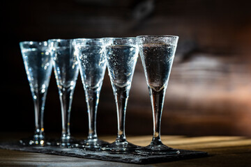 Selective focus of five shot glasses of cold vodka on wooden table, closeup
