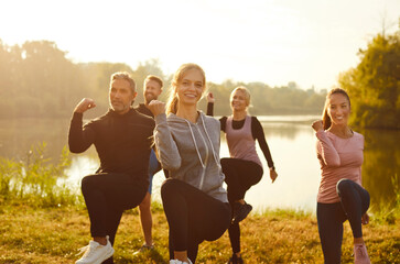 Group of fit and active people doing sport exercising in nature. Happy smiling men and women in...