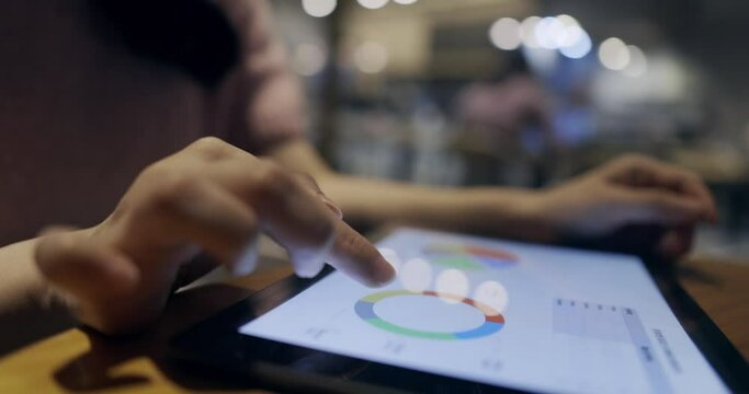 A businessman uses a digital tablet to check reports in a cafe