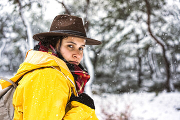 Young woman with yellow rain coat hiking in the forset on a snowy day