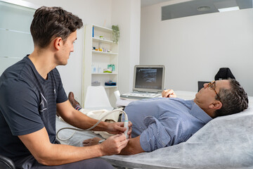Physiotherapist performs an ultrasound while looking at the machine