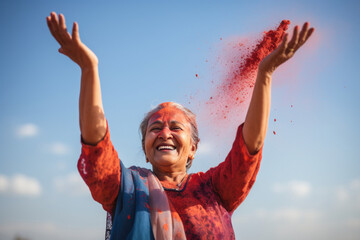 Fototapeta na wymiar Energetic woman scattering red Holi color in sunlight