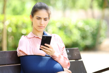 Worried convalescent woman checking phone in a park