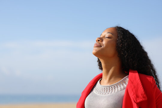 Black Woman In Red Breathing Fresh Air On The Beach In Winter