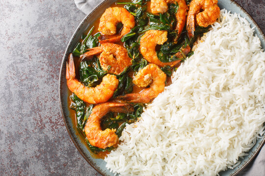 Shrimp curry cooked in a spinach, cream, spices, tomato, and ginger served with rice closeup on the plate on the table. Horizontal top view from above