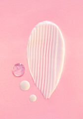 cosmetic smears of creamy texture drops of tonic serum on a pink background