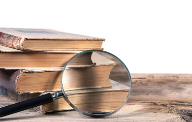 Old books and magnifying glass on textured wooden surface isolated on white background