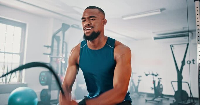 Gym, workout and black man with battle rope for muscle growth, strength development or speed exercise. Action, sports and bodybuilder resilience in functional training, fitness or endurance cardio