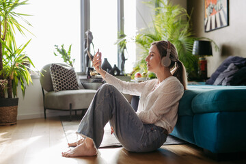 Female nurse or doctor enjoying free time at home after work, listening meditation relaxing music. Work-life balance for healthcare worker. - obrazy, fototapety, plakaty