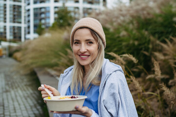 Nurse having healthy lunch, snack in front of hospital building, taking break from work. Importance...