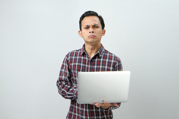 sad crying expression of asian indonesian man holding laptop computer on isolated background