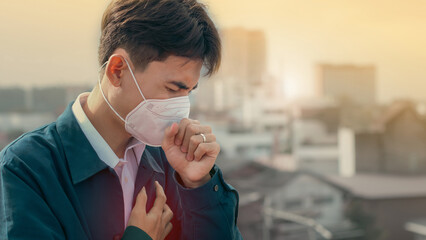 A young man wearing face masks to protect PM 2.5 smoke, city dust danger and air pollution in city,...