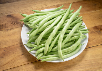 Fresh Bush bean or Fresh green beans on a white plate on wooden table.