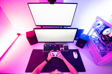 Hands of gamer holding gaming console and playing video game on desktop