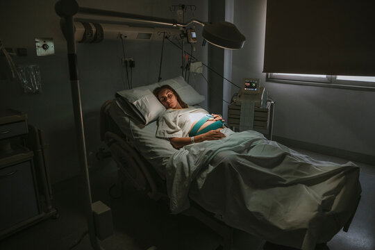 Pregnant woman sleeping on bed near equipment in delivery room at hospital