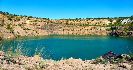 Old abandoned quarry lake filled with emerald water with radon