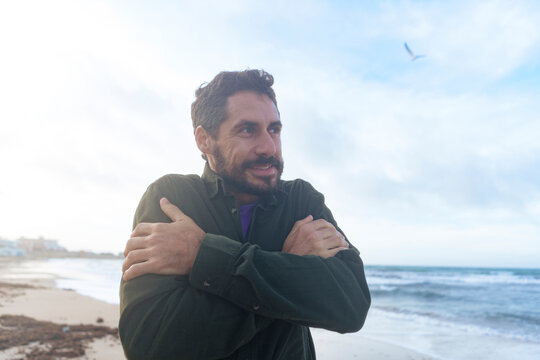 Happy man shivering and feeling cold at beach